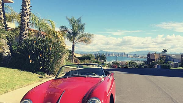 Red convertible with bay and city skyline behind